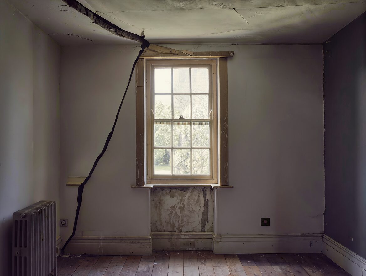Large structural crack running through a wall above a window