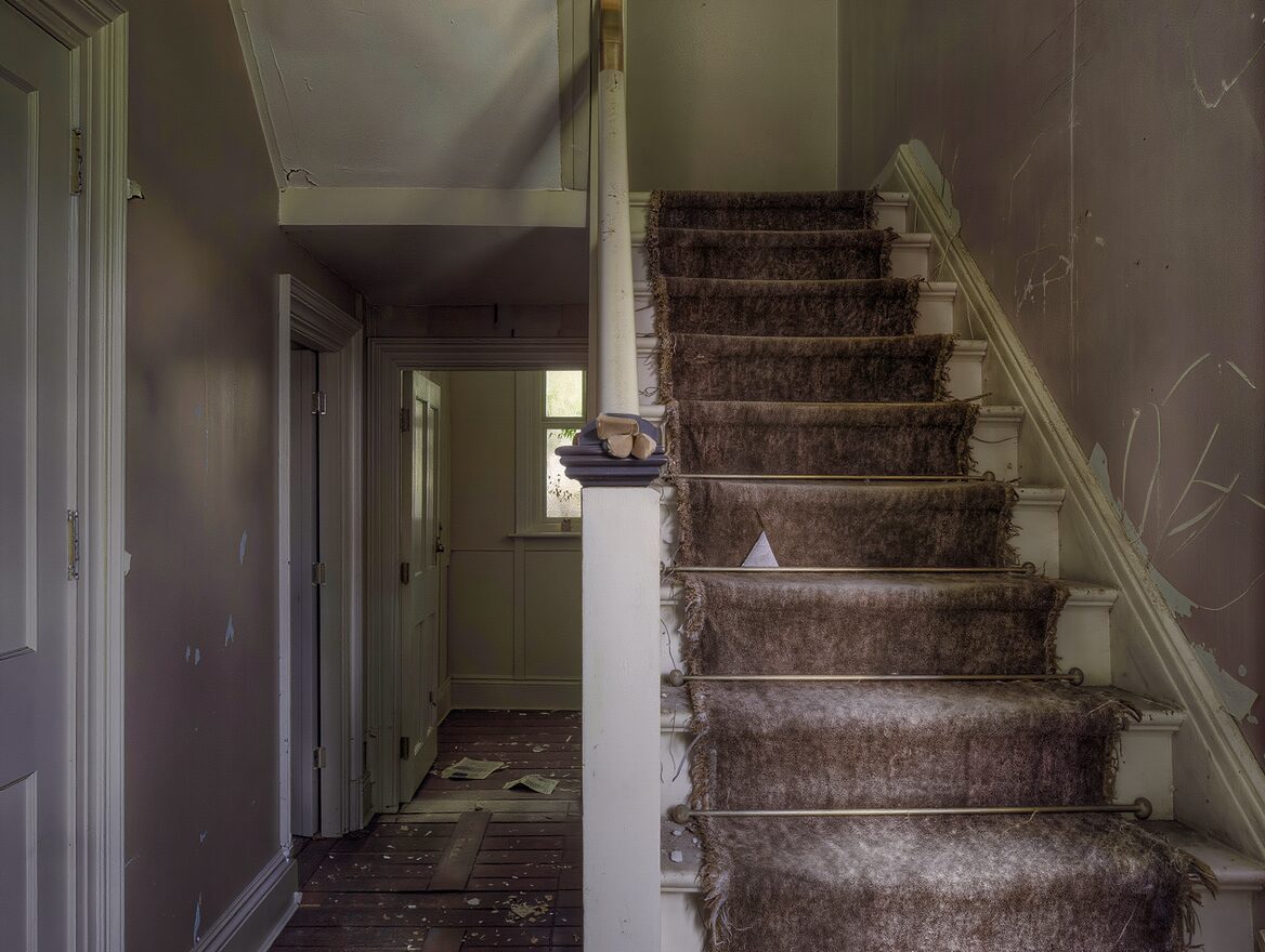 Worn and frayed stair carpet on a dim staircase